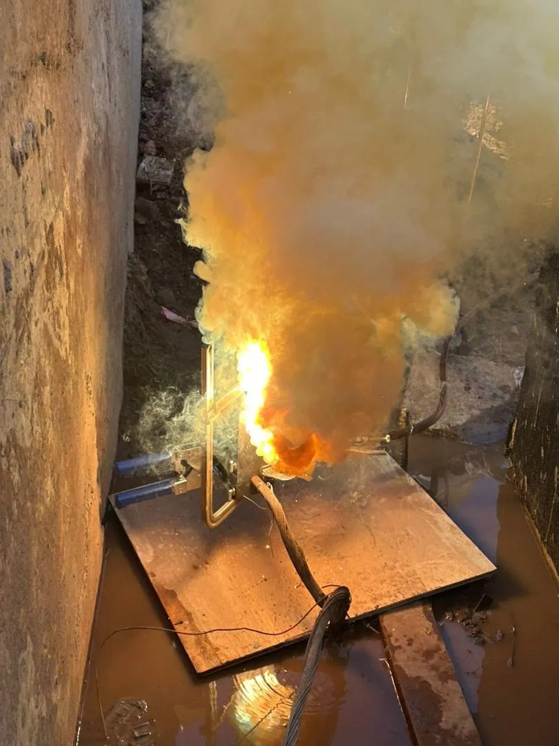 An exothermic weld firing inside its graphite mould to bond an earthing conductor.