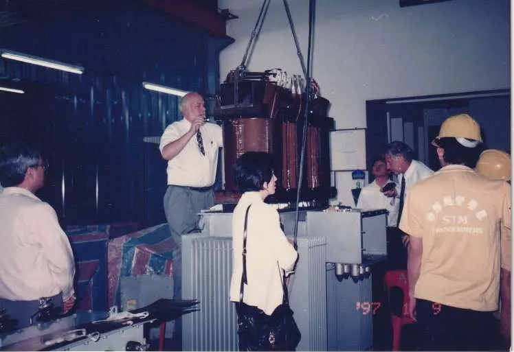 Engineers inspecting a transformer active part hoisted above its tank in the STM Transformers workshop in 1997.