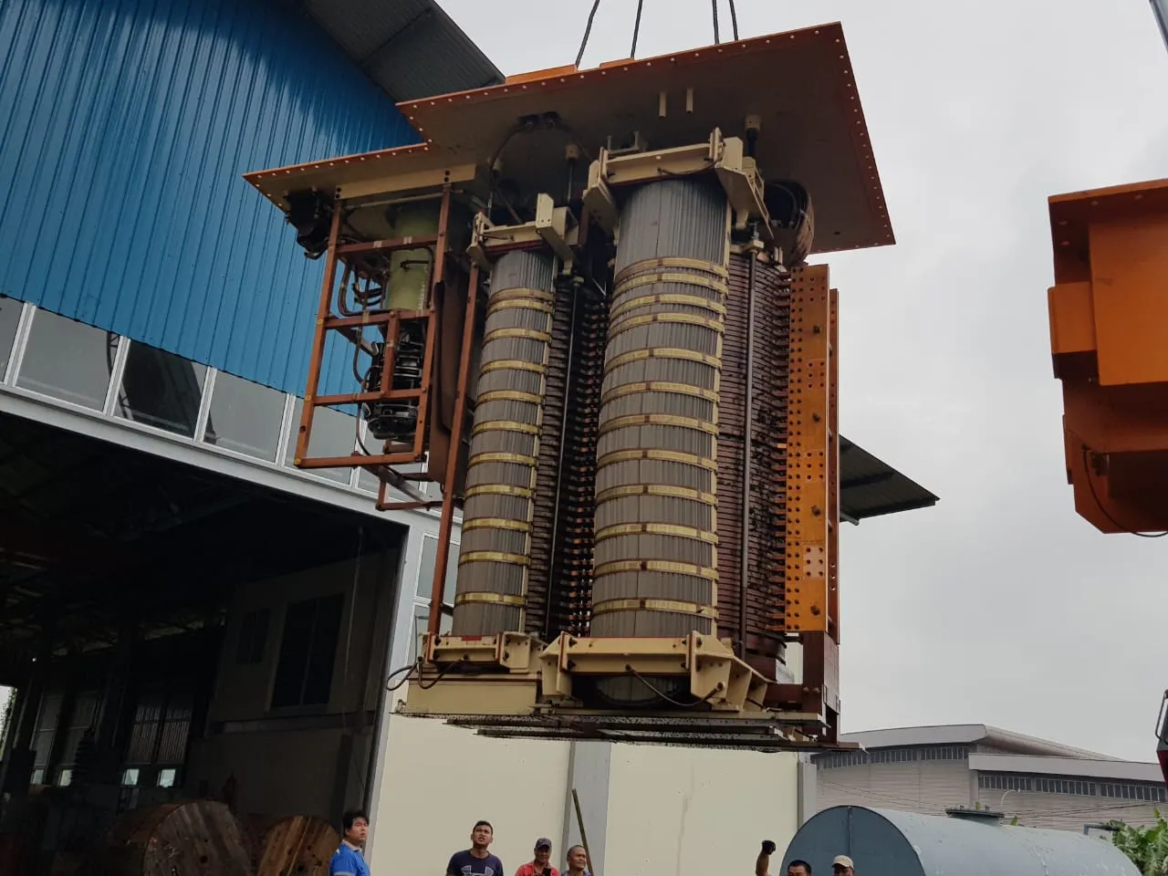 A transformer active part — core and windings — suspended from a crane outside the KTM Transformers workshop in Kuching.