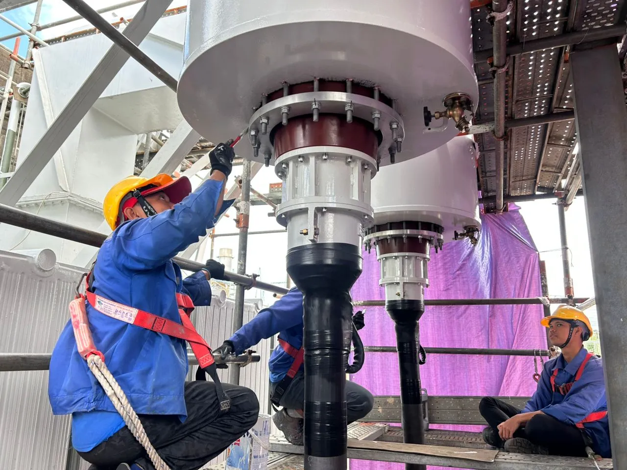 KTM Transformers technicians fitting a high-voltage bushing on a transformer.