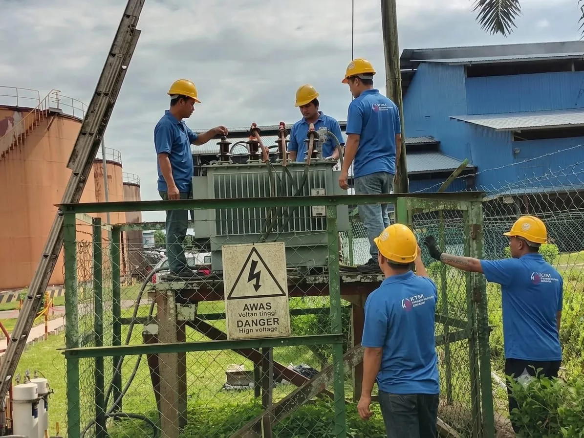 A KTM crew drawing transformer oil samples from a pole-mounted unit on site.