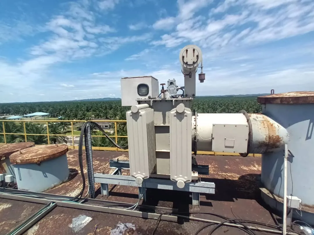 A pole-mounted distribution transformer in a plantation.